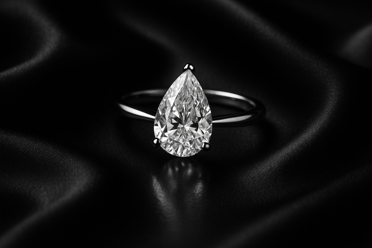 Luxury black and white editorial jewelry campaign photo of a solitaire engagement ring with pear shape lab-grown diamond in 18k white gold. Placed on black silk fabric with soft folds, dramatic cinematic lighting, subtle glossy reflection, timeless old money aesthetic, high-fashion magazine photography.