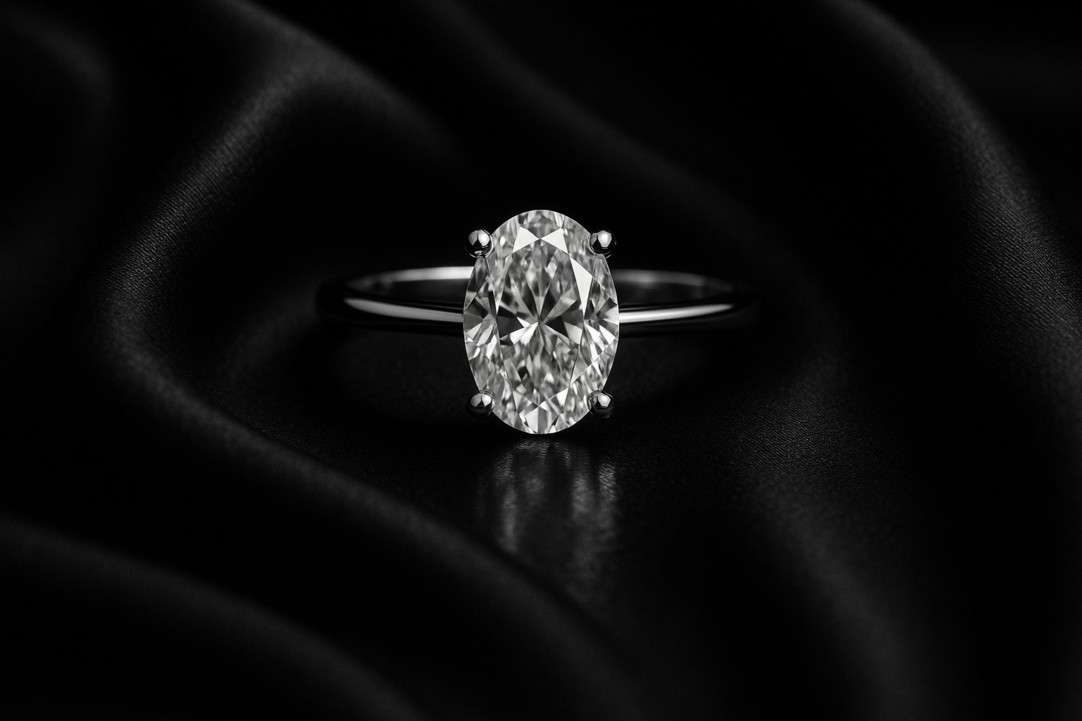 Luxury black and white editorial jewelry campaign photo of a solitaire engagement ring with oval lab-grown diamond in 18k white gold. Placed on black silk fabric with soft folds, dramatic cinematic lighting, subtle glossy reflection, timeless old money aesthetic, high-fashion magazine photography.